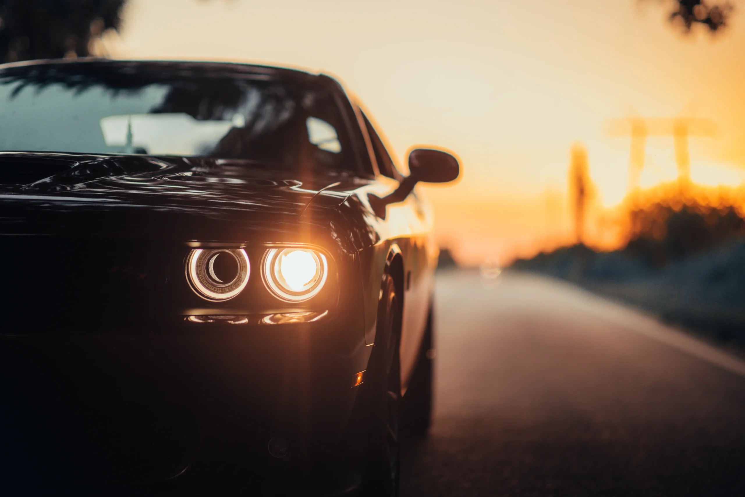 luxurious-car-parked-highway-with-illuminated-headlight-sunset